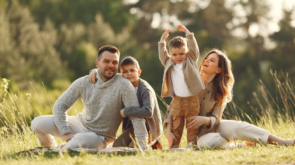 Family with cute little child. Father in a gray sweater. Sunset background.