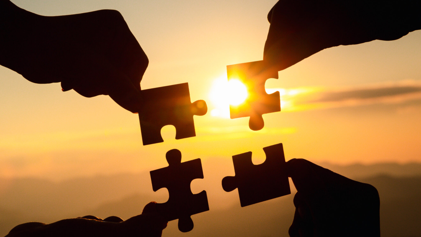 Silhouette  hands connecting  jigsaw puzzle piece against sunrise, Business solutions,  teamwork, partnership, success, goals and strategy concepts.